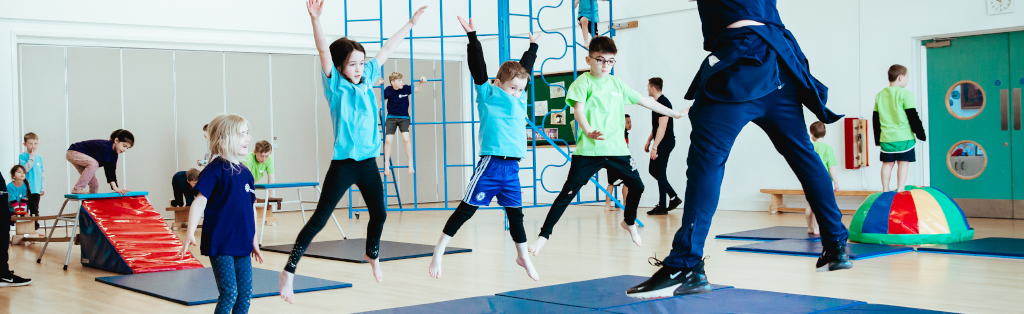Children jumping for joy in a Premier Education gymnastics after-school club.