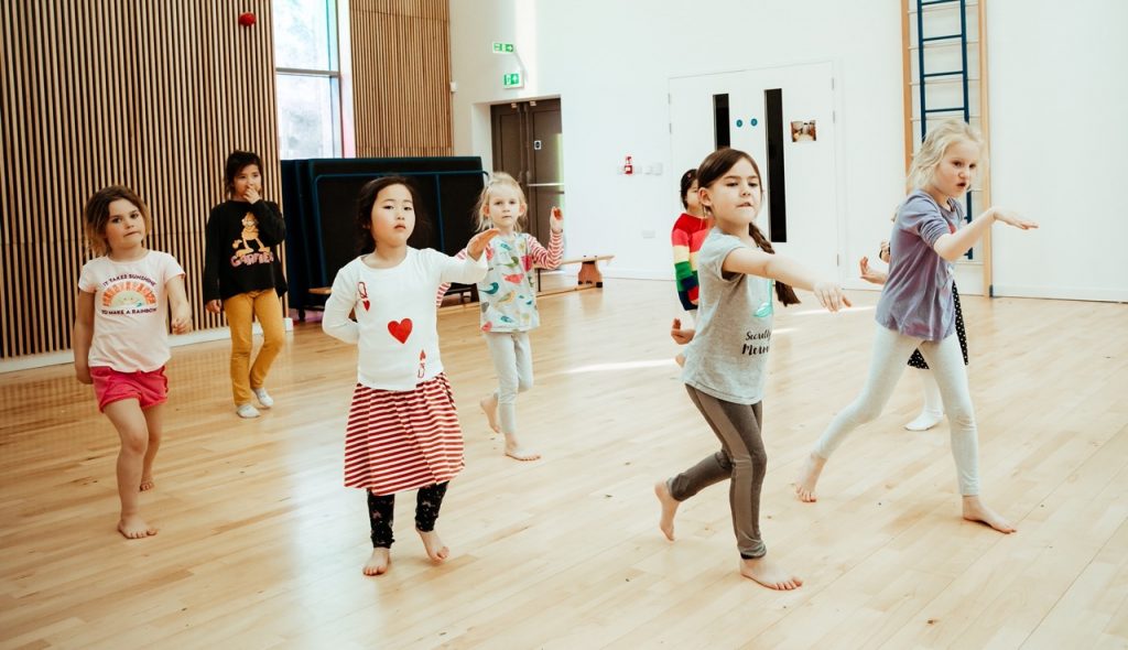 Pupils pointing their hands forward in the middle of a dance class