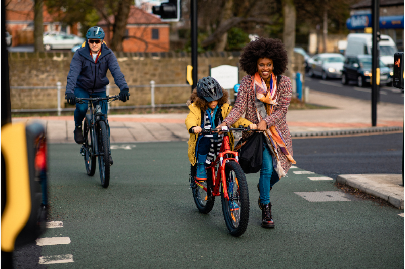 7 tips for teaching road safety to children 1 Woman helping child on bike cross the road at traffic lights